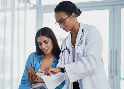 Female practitioner pointing to something on cell phone for female patient