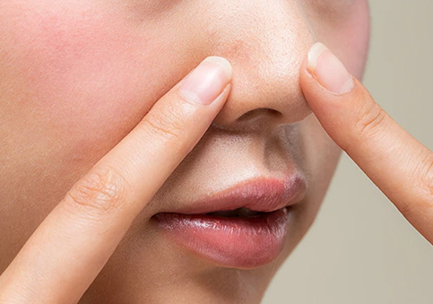 Close-up of fingers pointing to nose