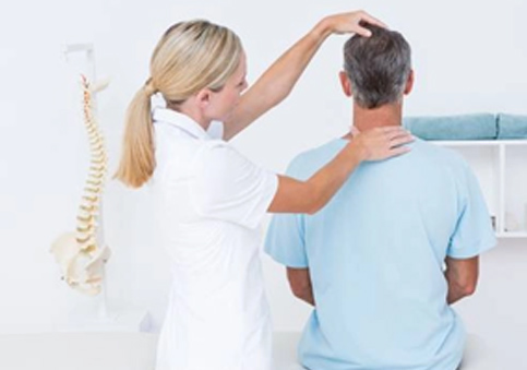 Female practitioner assessing seated male patient's head and neck