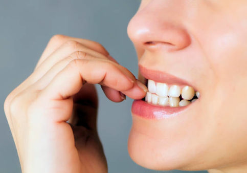 Close-up of teeth biting fingernails