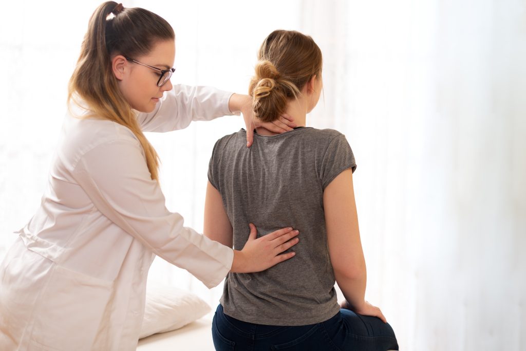 Female physiotherapist or a chiropractor examining patients back