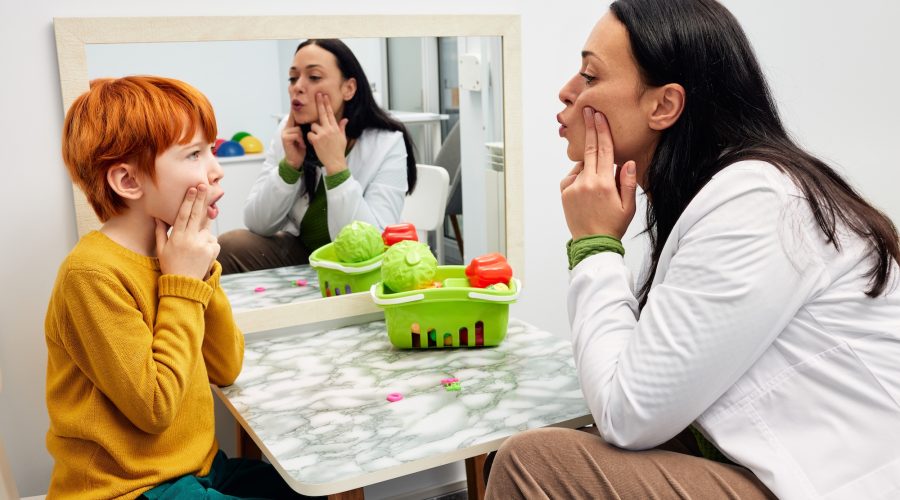 myofunctional therapy. Therapist shaping a boy's mouth in order for his to make correct sound